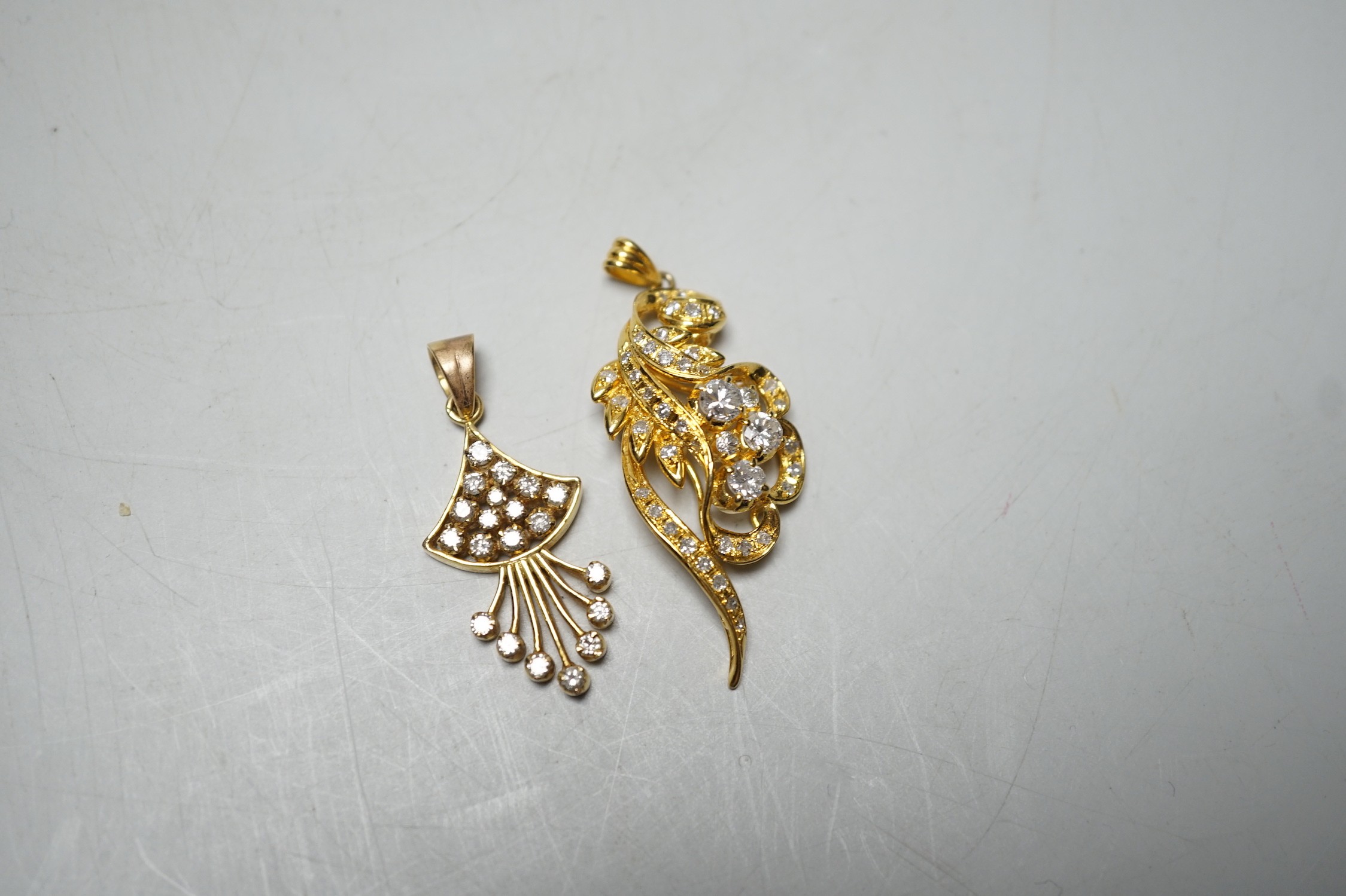 An Earl 18k yellow metal and diamond cluster ser scrolling pendant, overall 46mm and a yellow metal and diamond cluster set fan shaped pendant, gross weight 11.8 grams.